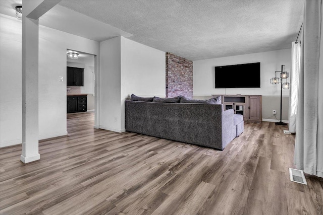 living area featuring a textured ceiling, baseboards, and wood finished floors