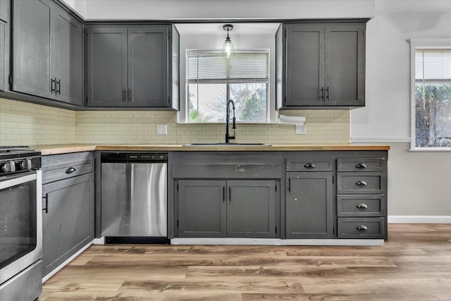 kitchen with a sink, stainless steel appliances, gray cabinetry, and light wood finished floors