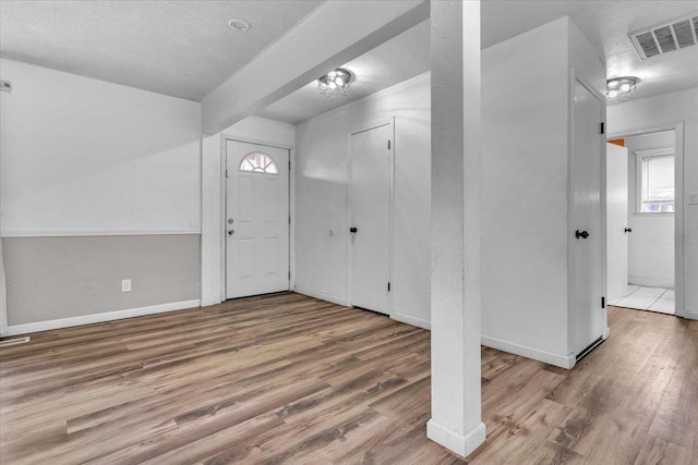 entryway with visible vents, baseboards, a textured ceiling, and wood finished floors