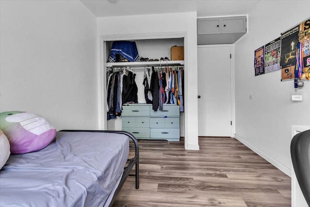 bedroom with wood finished floors, a closet, and baseboards