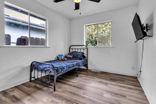 bedroom featuring ceiling fan, baseboards, and wood finished floors