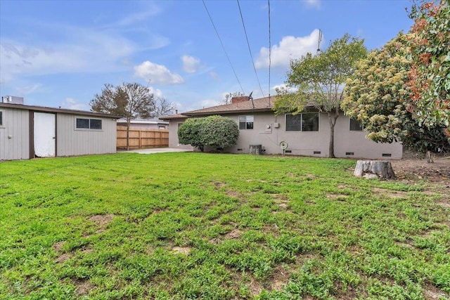 exterior space with crawl space, a lawn, an outdoor structure, and fence