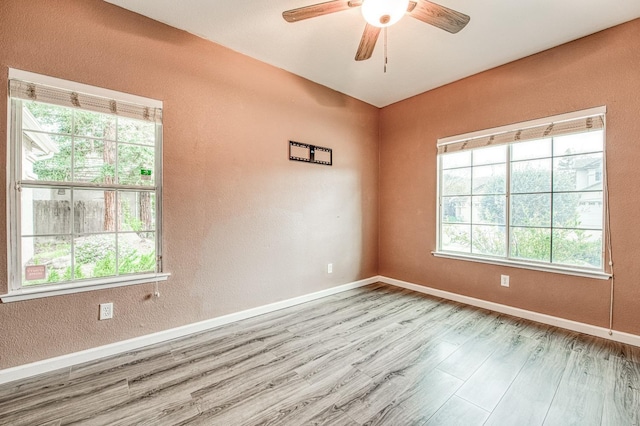 spare room featuring wood finished floors, baseboards, a textured wall, and ceiling fan