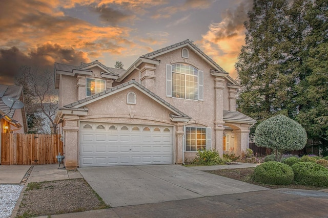 view of front facade with fence, stucco siding, concrete driveway, a garage, and a tile roof