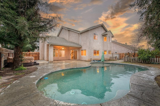 pool at dusk with a fenced backyard, a fenced in pool, and a patio