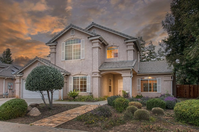 view of front of property featuring stucco siding, driveway, fence, a garage, and a tiled roof