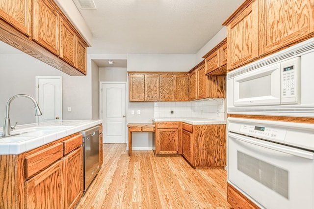 kitchen featuring white appliances, tile countertops, visible vents, light wood-style flooring, and a sink