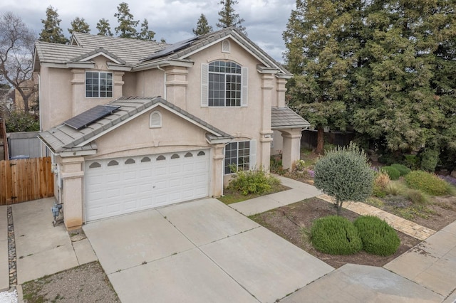 view of front of property with solar panels, fence, a tiled roof, stucco siding, and driveway