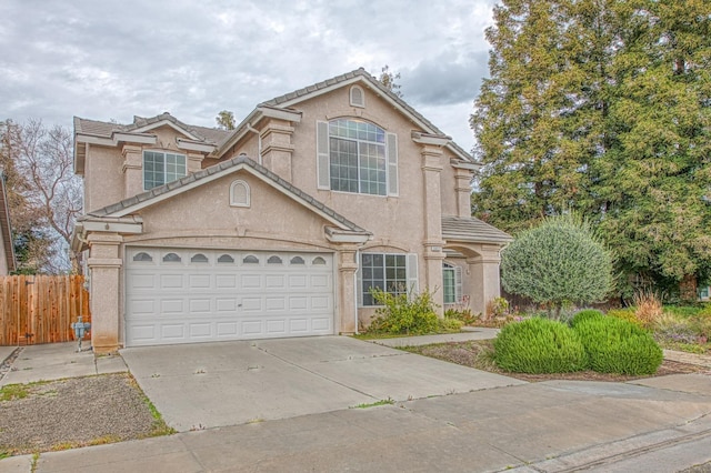 traditional home with stucco siding, a tile roof, fence, concrete driveway, and a garage