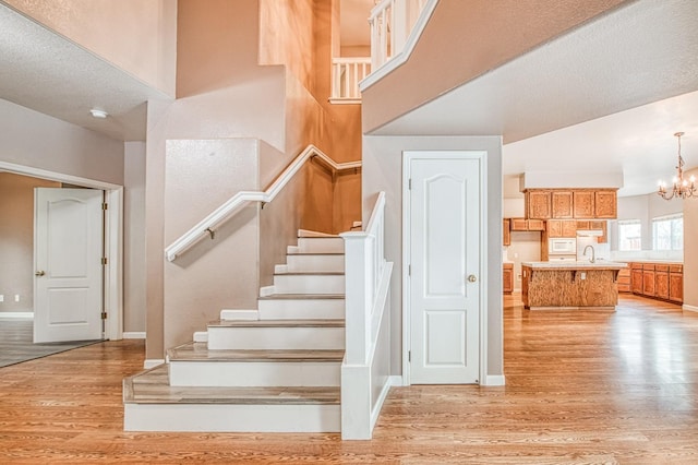 stairs with baseboards, a notable chandelier, and wood finished floors