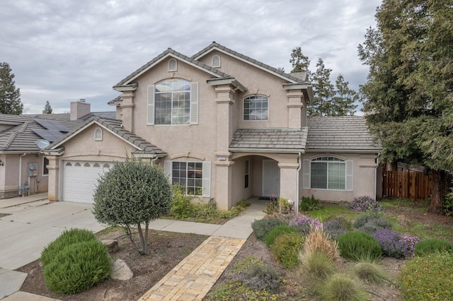 view of front facade with stucco siding, an attached garage, driveway, and fence