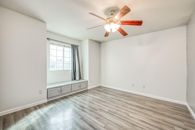 spare room featuring a ceiling fan, light wood-style floors, and baseboards