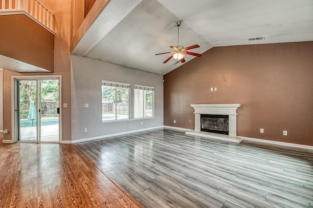 unfurnished living room with a glass covered fireplace, baseboards, wood finished floors, and a ceiling fan