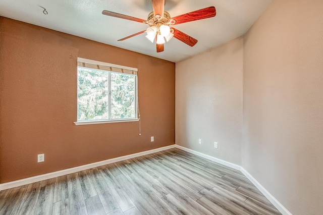 unfurnished room featuring a ceiling fan, wood finished floors, and baseboards