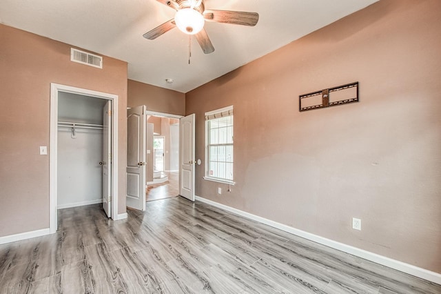 unfurnished bedroom featuring visible vents, baseboards, wood finished floors, a closet, and a ceiling fan