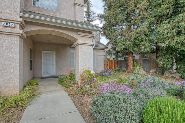 doorway to property with fence and stucco siding