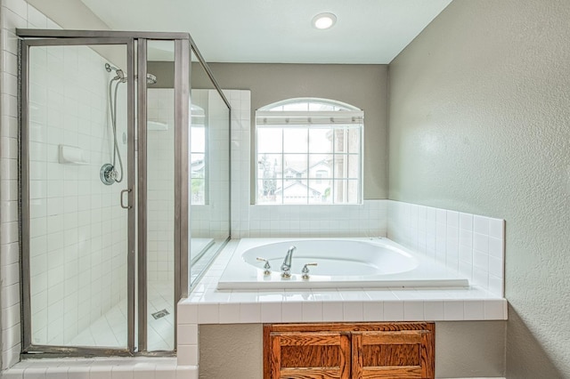 bathroom featuring a bath, a shower stall, and a textured wall