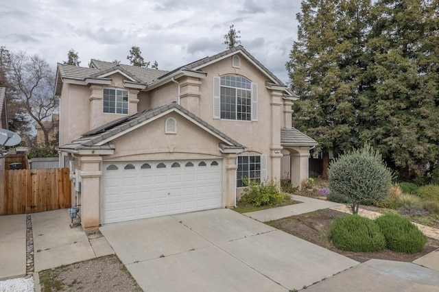 traditional home with fence, driveway, an attached garage, stucco siding, and a tile roof