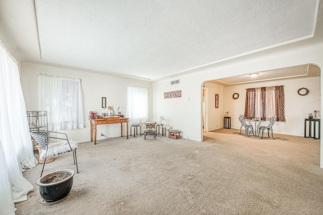 sitting room with visible vents, arched walkways, a textured ceiling, and carpet flooring