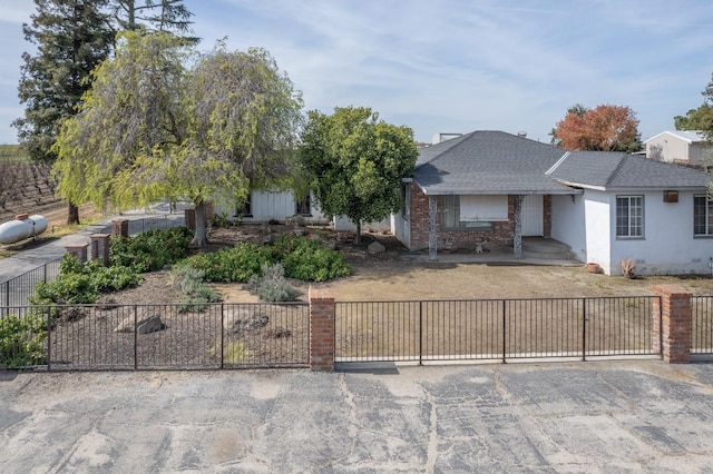 ranch-style home featuring a fenced front yard, stucco siding, and roof with shingles