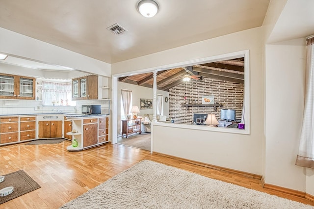 kitchen featuring visible vents, open shelves, lofted ceiling with beams, brown cabinetry, and light wood finished floors