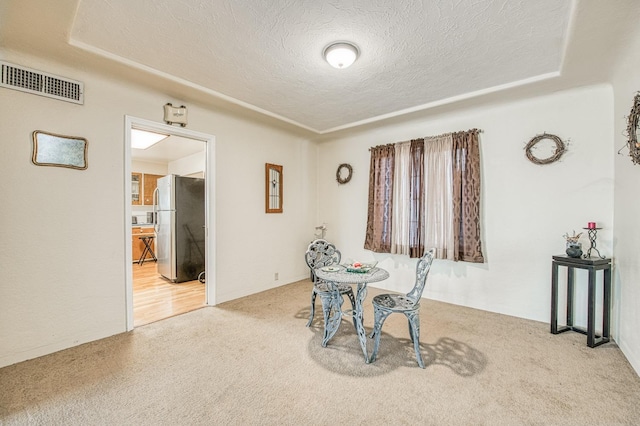 dining area featuring visible vents, carpet, and a textured ceiling