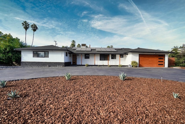 view of front of property with a garage, solar panels, and driveway