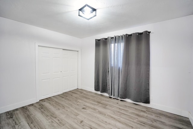 unfurnished bedroom with a closet, light wood-type flooring, and baseboards