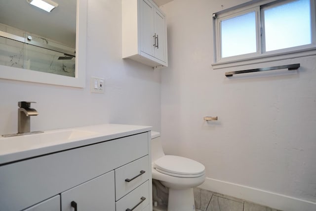 bathroom featuring a shower with door, toilet, vanity, and baseboards