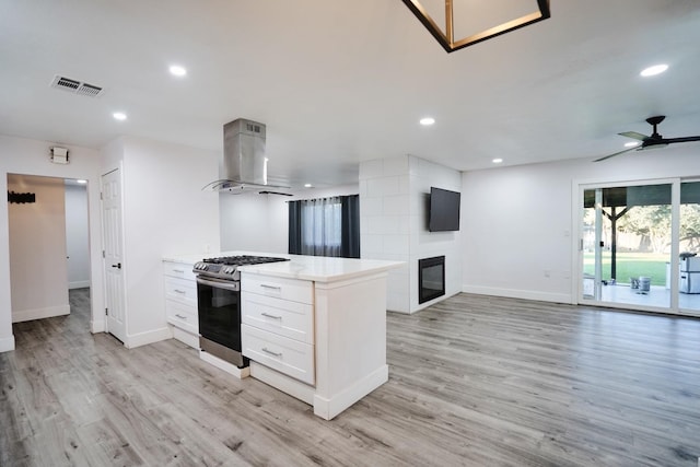 kitchen featuring stainless steel range with gas stovetop, recessed lighting, open floor plan, and island range hood