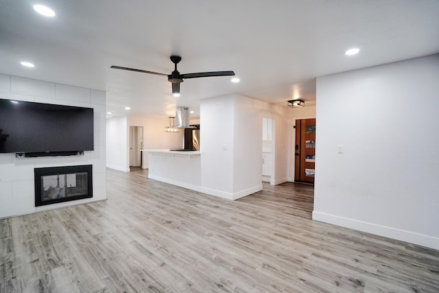 unfurnished living room with light wood-style flooring, recessed lighting, baseboards, and a multi sided fireplace