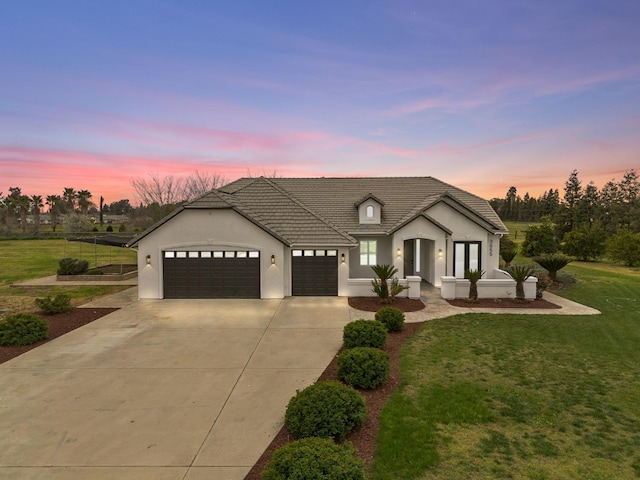 view of front facade featuring stucco siding, an attached garage, driveway, and a front yard