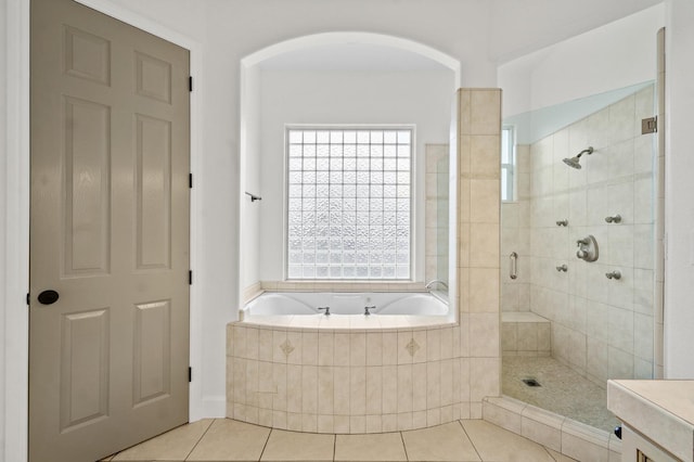 full bath featuring tile patterned flooring, plenty of natural light, a shower stall, and a garden tub