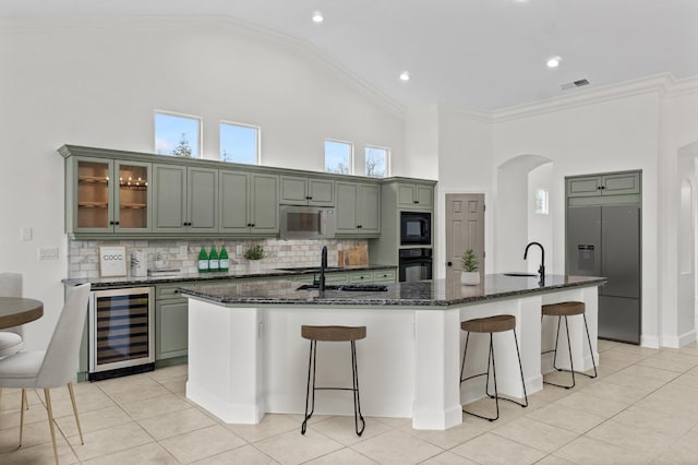 kitchen with visible vents, black appliances, beverage cooler, a breakfast bar, and arched walkways