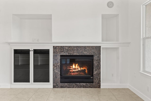 details featuring a glass covered fireplace and baseboards