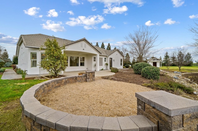 rear view of house with a patio, a tiled roof, and stucco siding