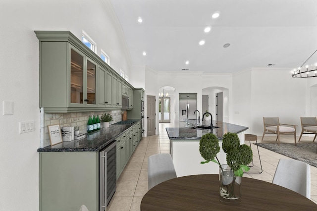 kitchen with arched walkways, wine cooler, green cabinets, a chandelier, and stainless steel built in refrigerator