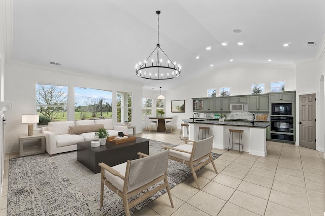 living area with a notable chandelier, light tile patterned flooring, visible vents, and ornamental molding