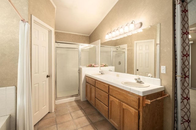 full bathroom with double vanity, a stall shower, and a sink