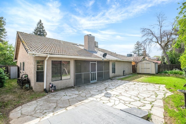 rear view of house featuring a storage unit, stucco siding, a patio, fence, and an outdoor structure