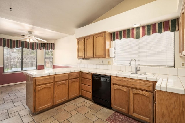 kitchen with stone finish floor, a sink, a peninsula, dishwasher, and ceiling fan