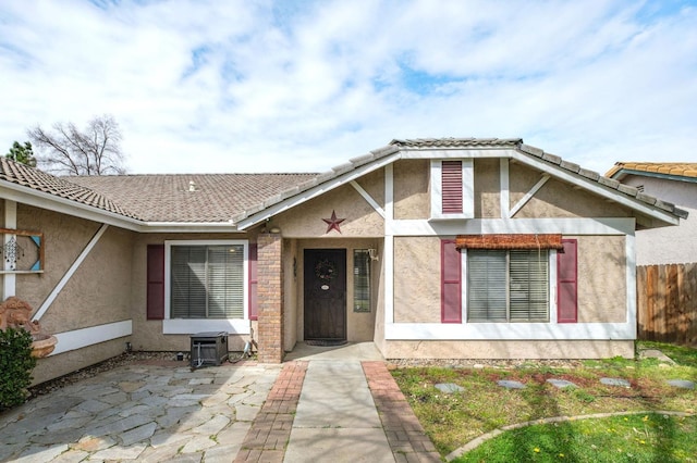 view of front of house with a tiled roof, fence, and stucco siding