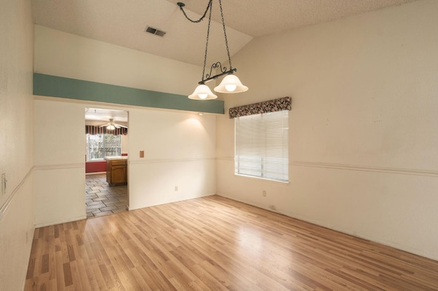 unfurnished room featuring a ceiling fan, visible vents, lofted ceiling, light wood-style floors, and a textured ceiling