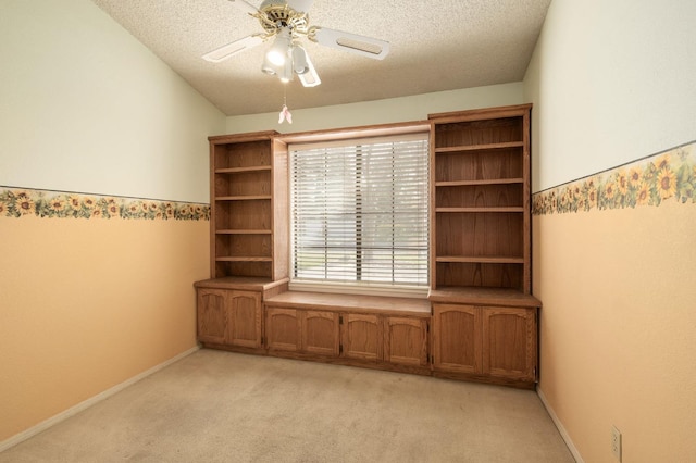 spare room with ceiling fan, a textured ceiling, baseboards, and light carpet