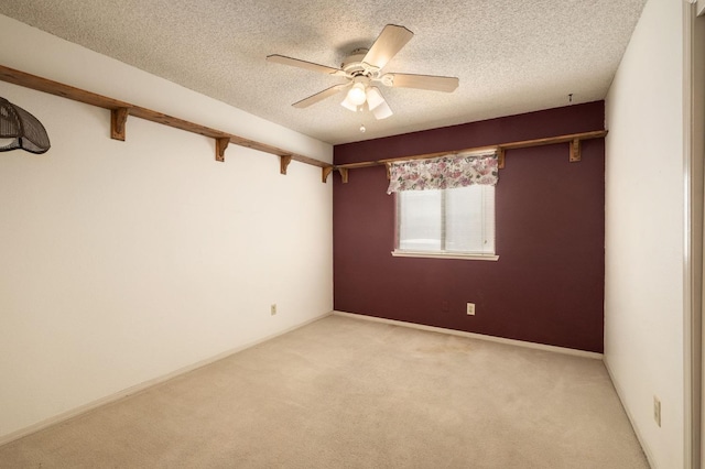 spare room with baseboards, ceiling fan, beamed ceiling, light carpet, and a textured ceiling