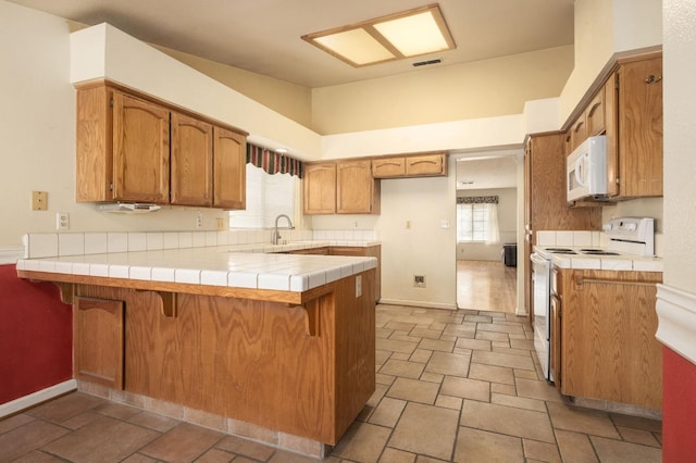 kitchen with visible vents, tile countertops, white appliances, and a peninsula