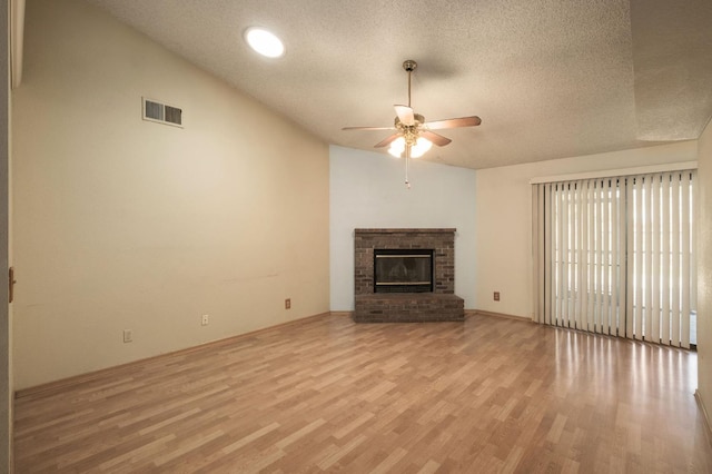 unfurnished living room with visible vents, ceiling fan, vaulted ceiling, light wood-style flooring, and a textured ceiling