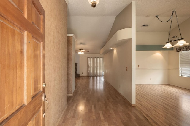 hallway featuring wood finished floors, visible vents, and high vaulted ceiling