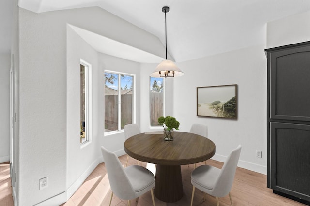 dining space featuring baseboards, lofted ceiling, and light wood-style floors