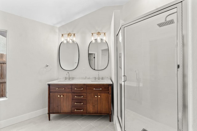 bathroom featuring a sink, a stall shower, double vanity, and vaulted ceiling